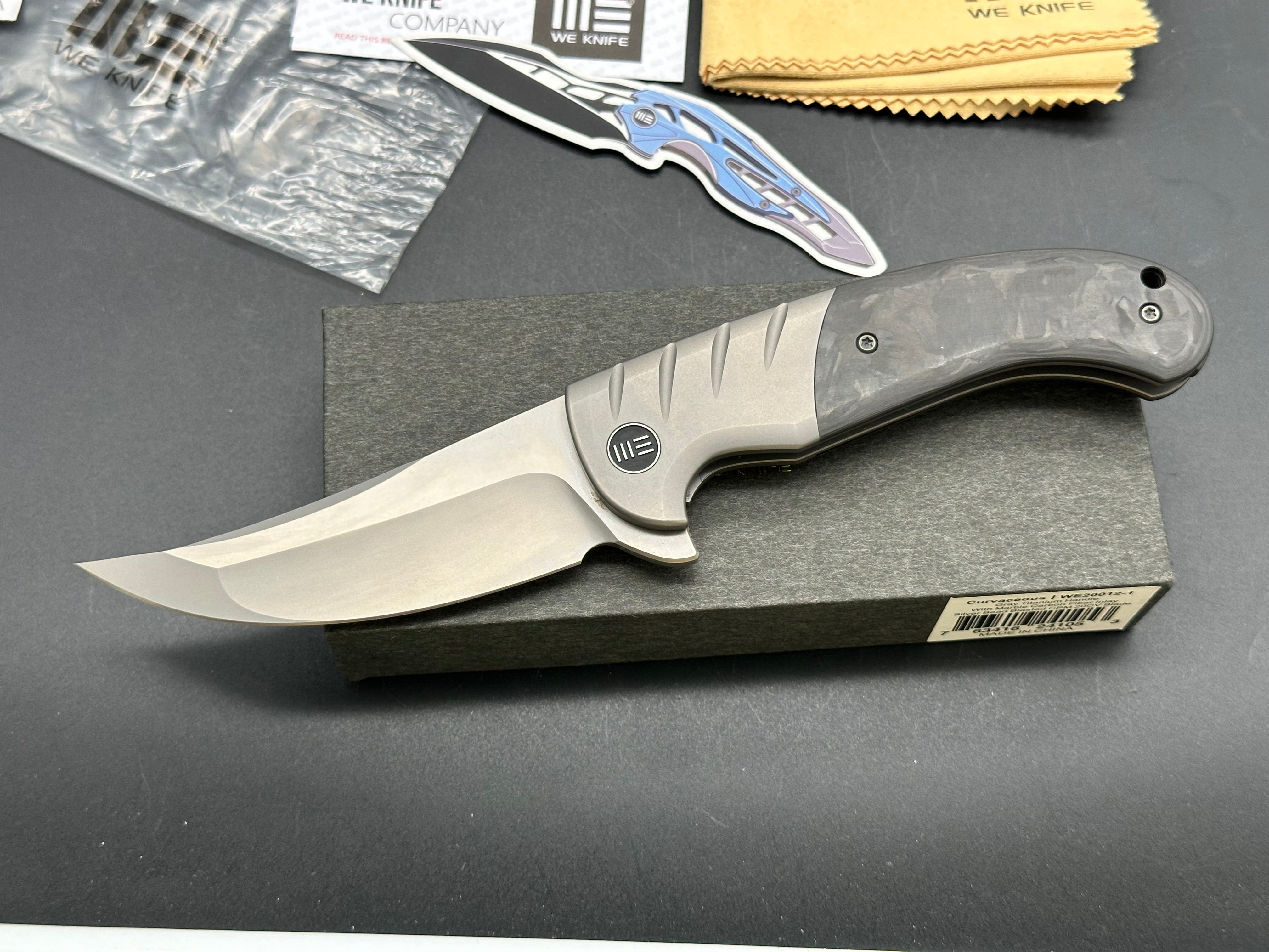 WE CURVACEOUS FOLDING KNIFE TITANIUM/MARBLE CARBON FIBER HANDLE 20CV PLAIN EDGE