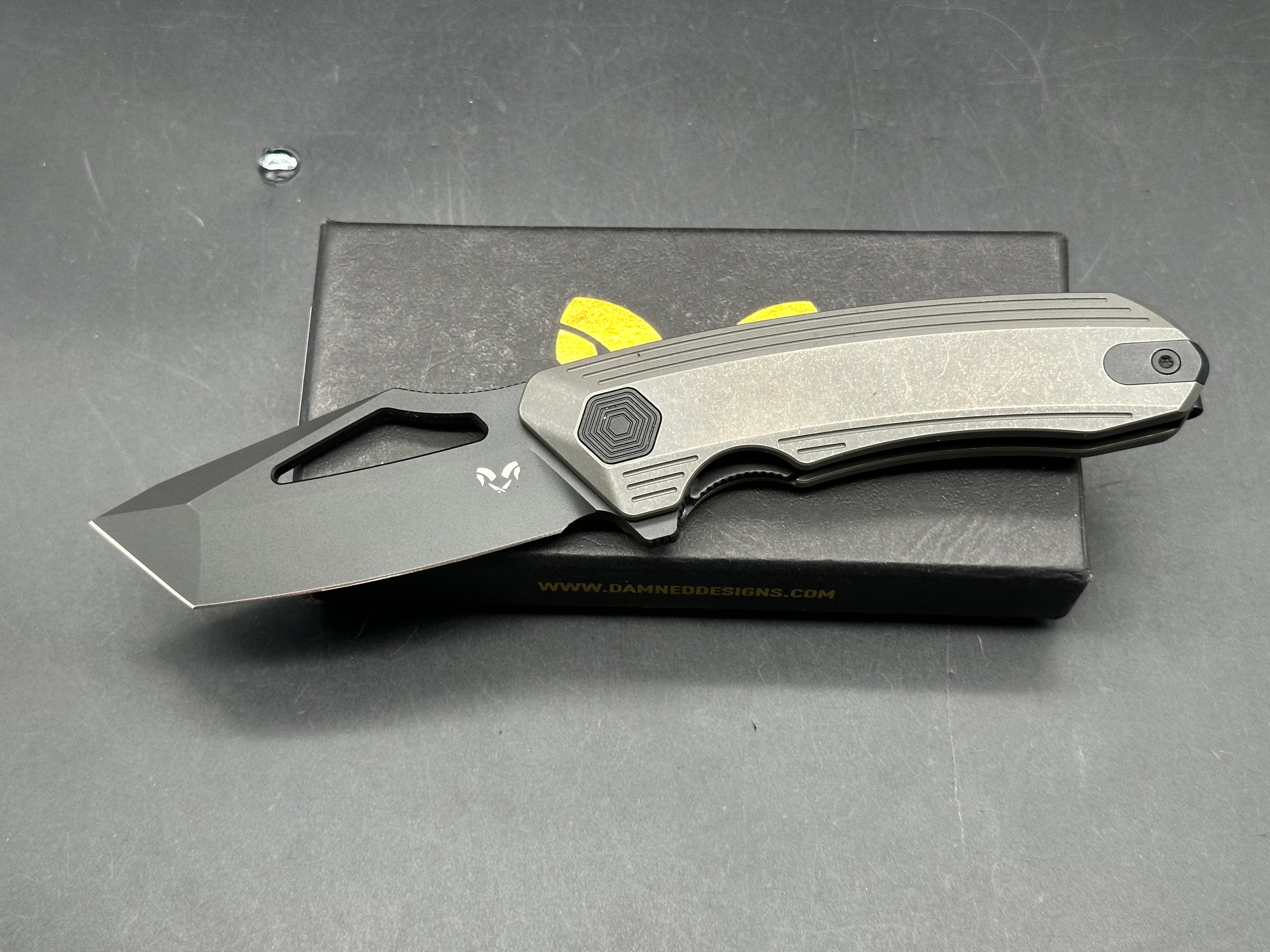 Damned Designs Banshee: 3.1 inch hollow grind, stonewashed, blackwashed CPM-S35VN blade. Ceramic ball bearings