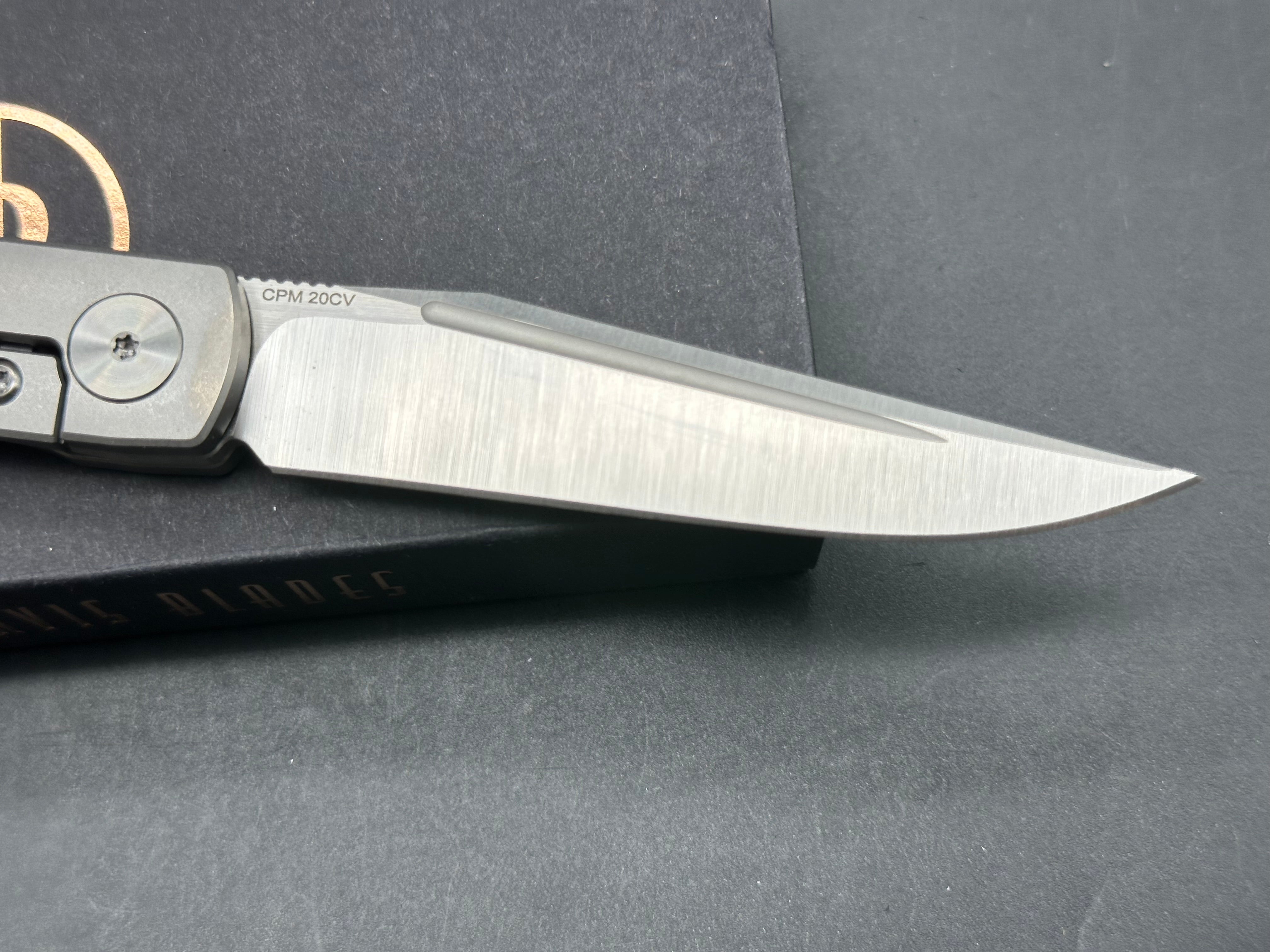 Adam Purvis Rook 3.3 inch vertical belt sanded CPM-20CV blade. Titaniu scales with marbled carbon fiber inlays. Satin hardware
