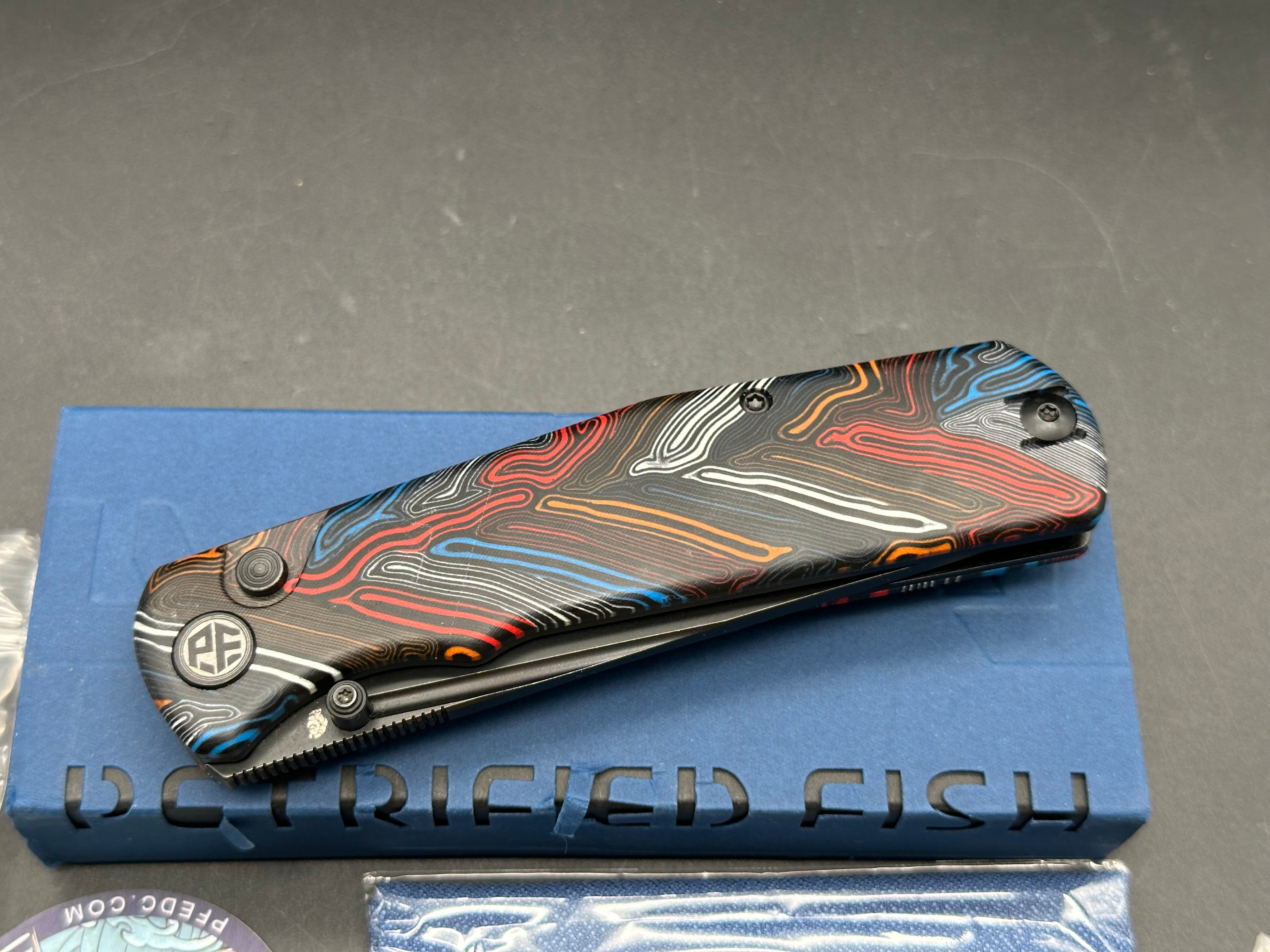 PETRIFIED FISH LIS FOLDING KNIFE BUTTON MULTI COLOR HANDLE 10CR15COMOV BLACK BLADE