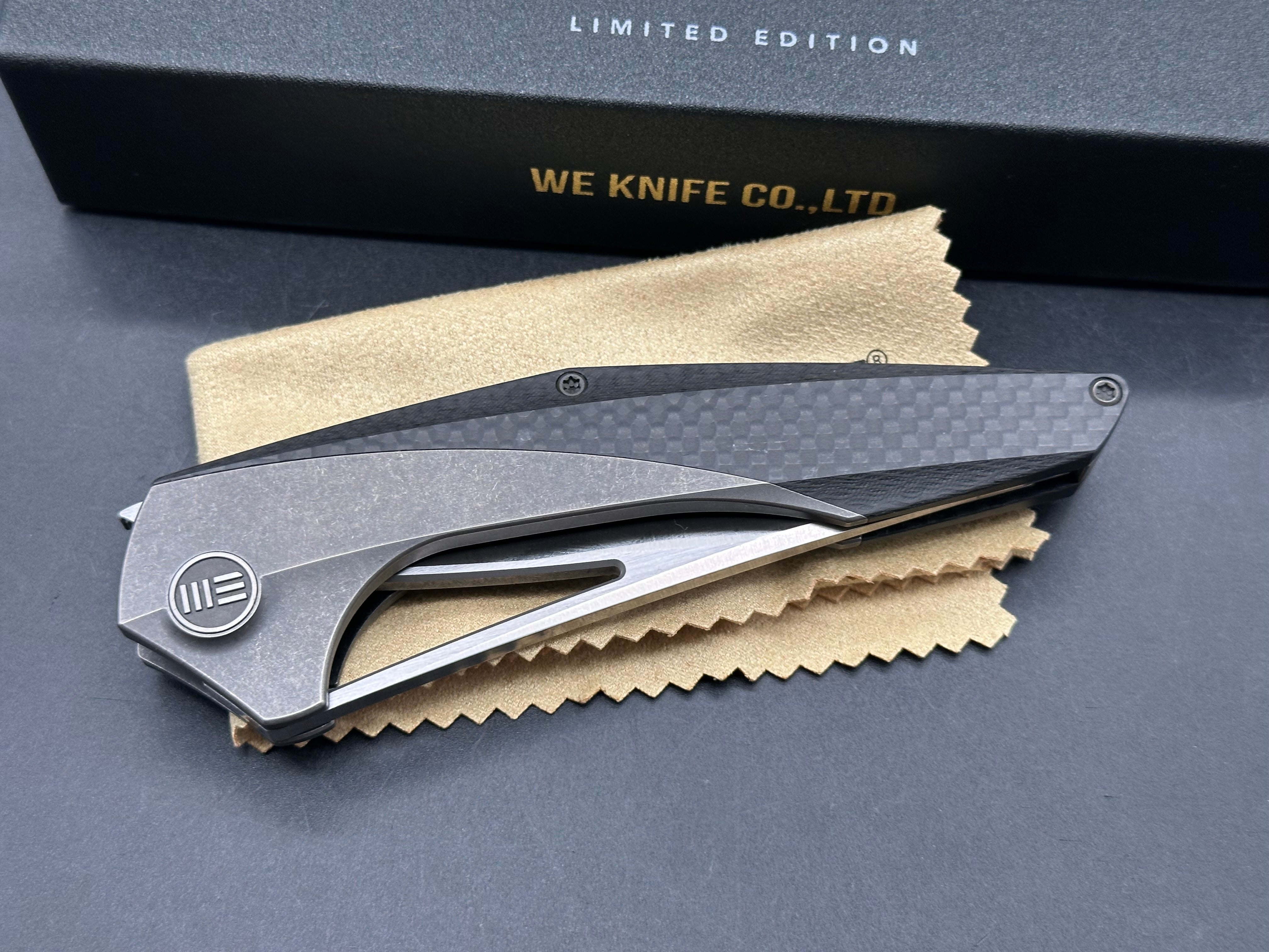 We Zeta: Elijah Isham design. 3.875 inch M390, trailing point, flat grind, satin finish blade. Frame lock. Carbon fiber and titanium handle
