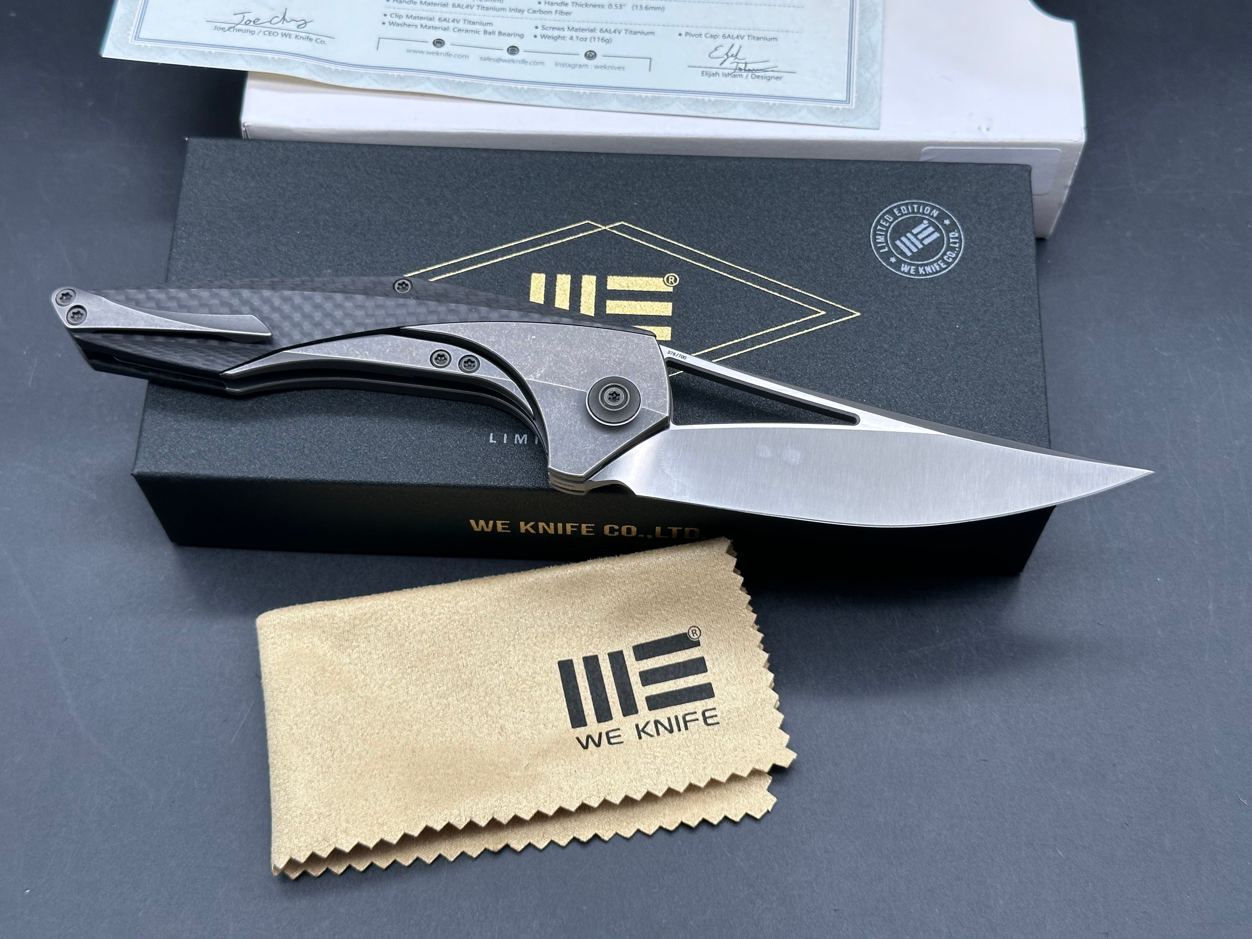We Zeta: Elijah Isham design. 3.875 inch M390, trailing point, flat grind, satin finish blade. Frame lock. Carbon fiber and titanium handle