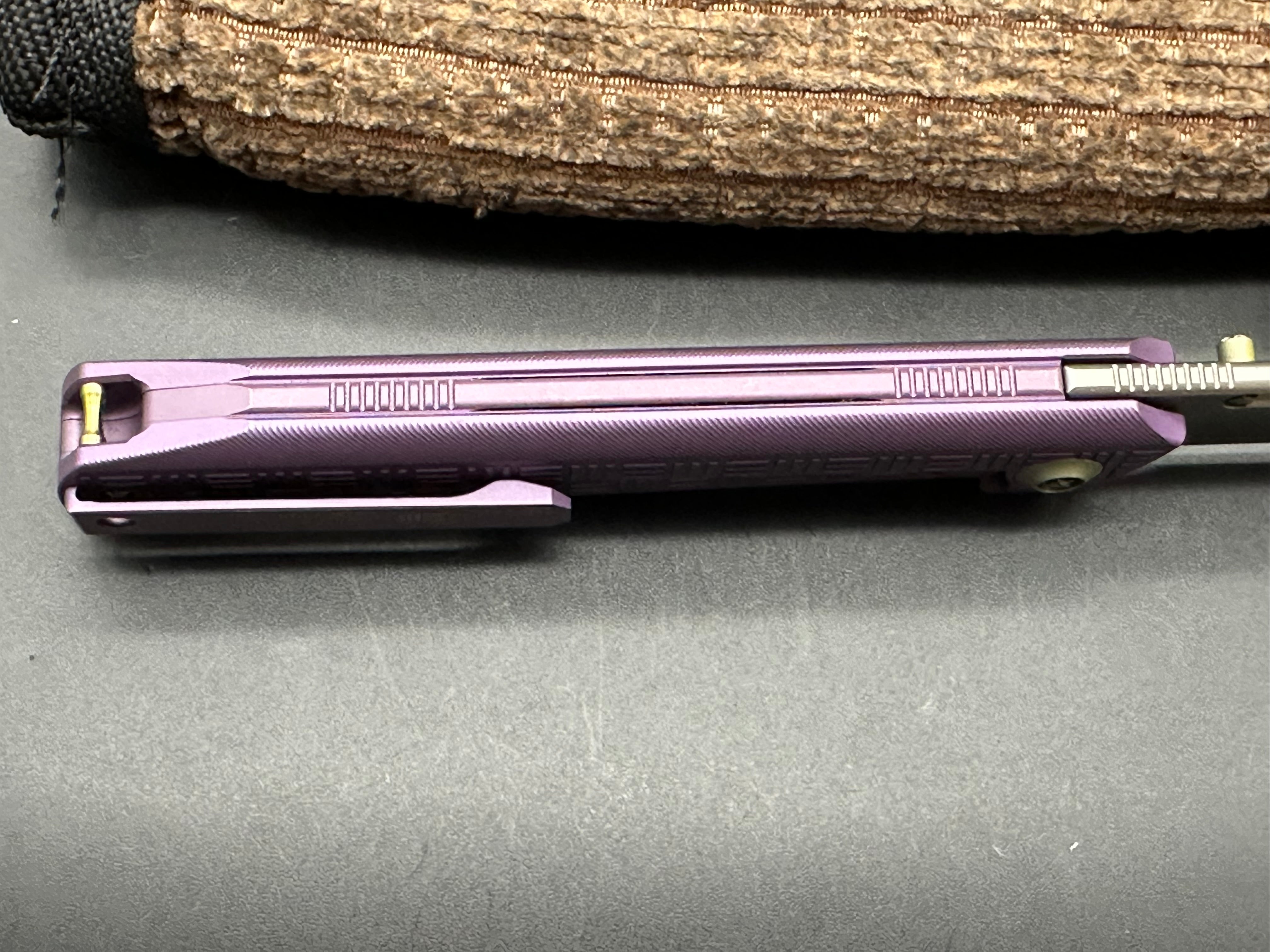 We 710B: 3.85 inch, flat grind, satin, M390 blade. Purple anodized handle. Frame lock. Ceramic bearings