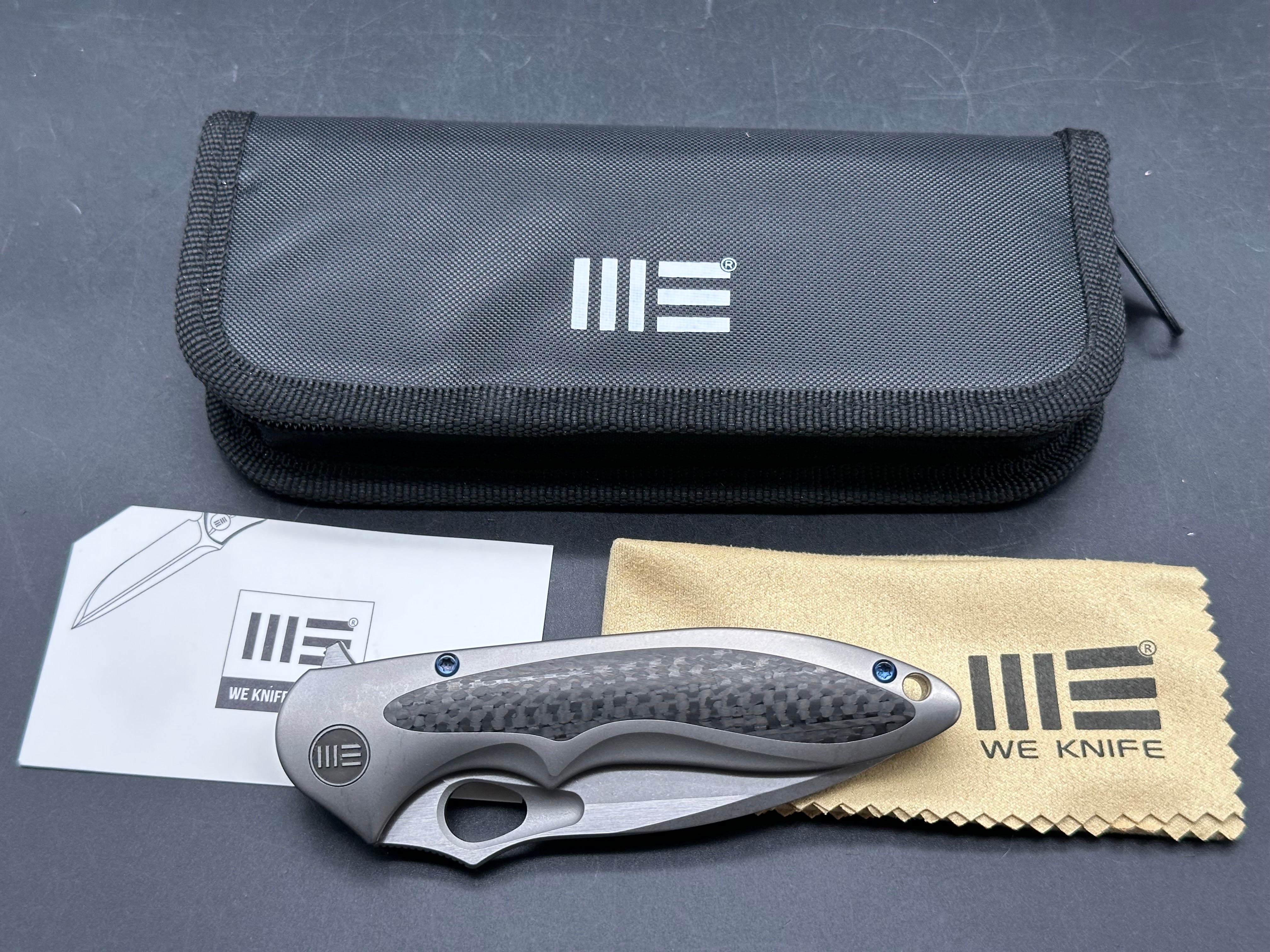 We Knives Zephyr: 3.5 inch drop point, flat grind, Bohler M390 blade. Titanium handle with carbon fiber inset