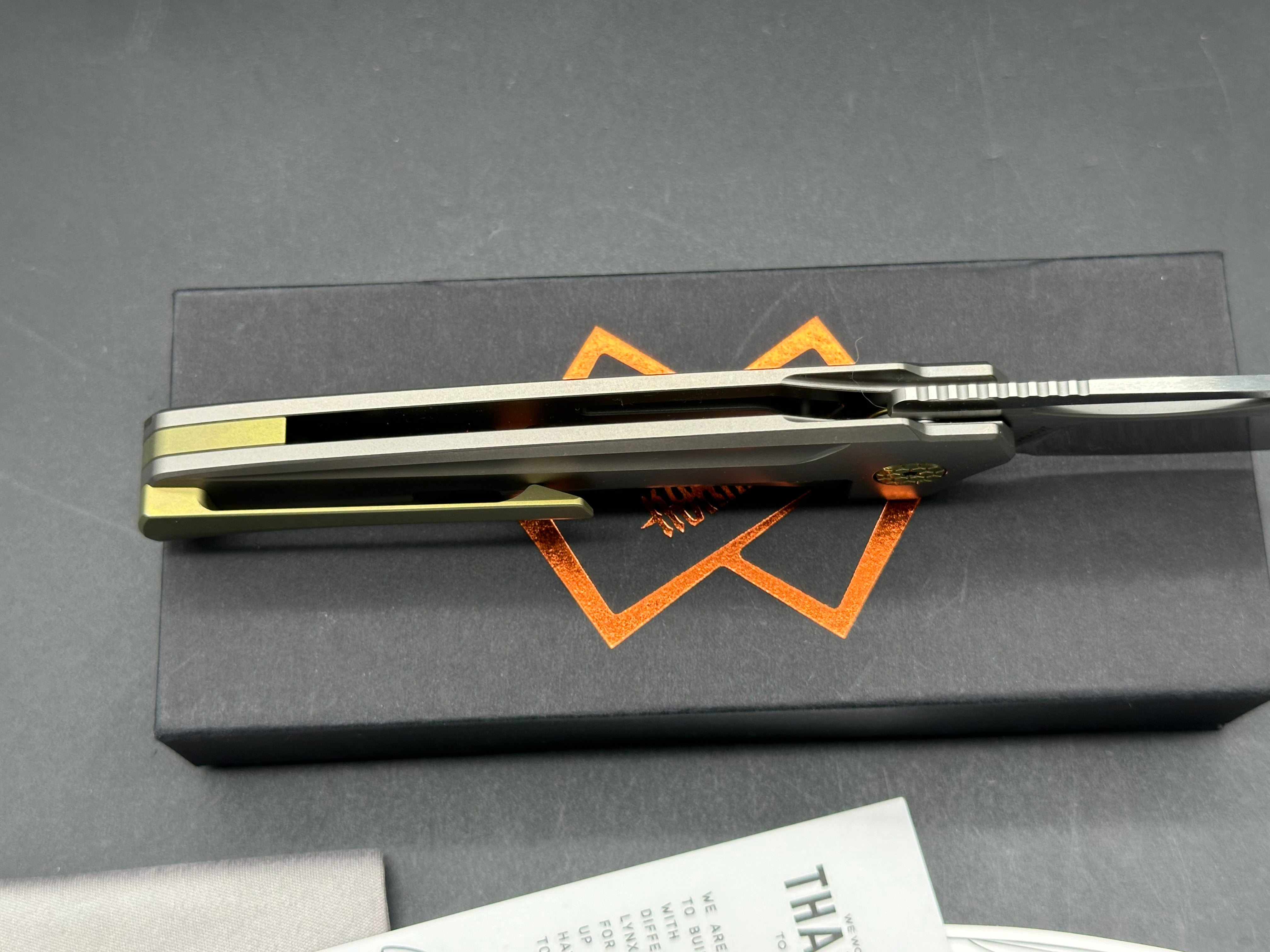 The Matsey + Kombou Lynx Grey Ti Handle + Gold Marble CF w/ Gold Ano Accents/Drop Point/Satin Mangnacut