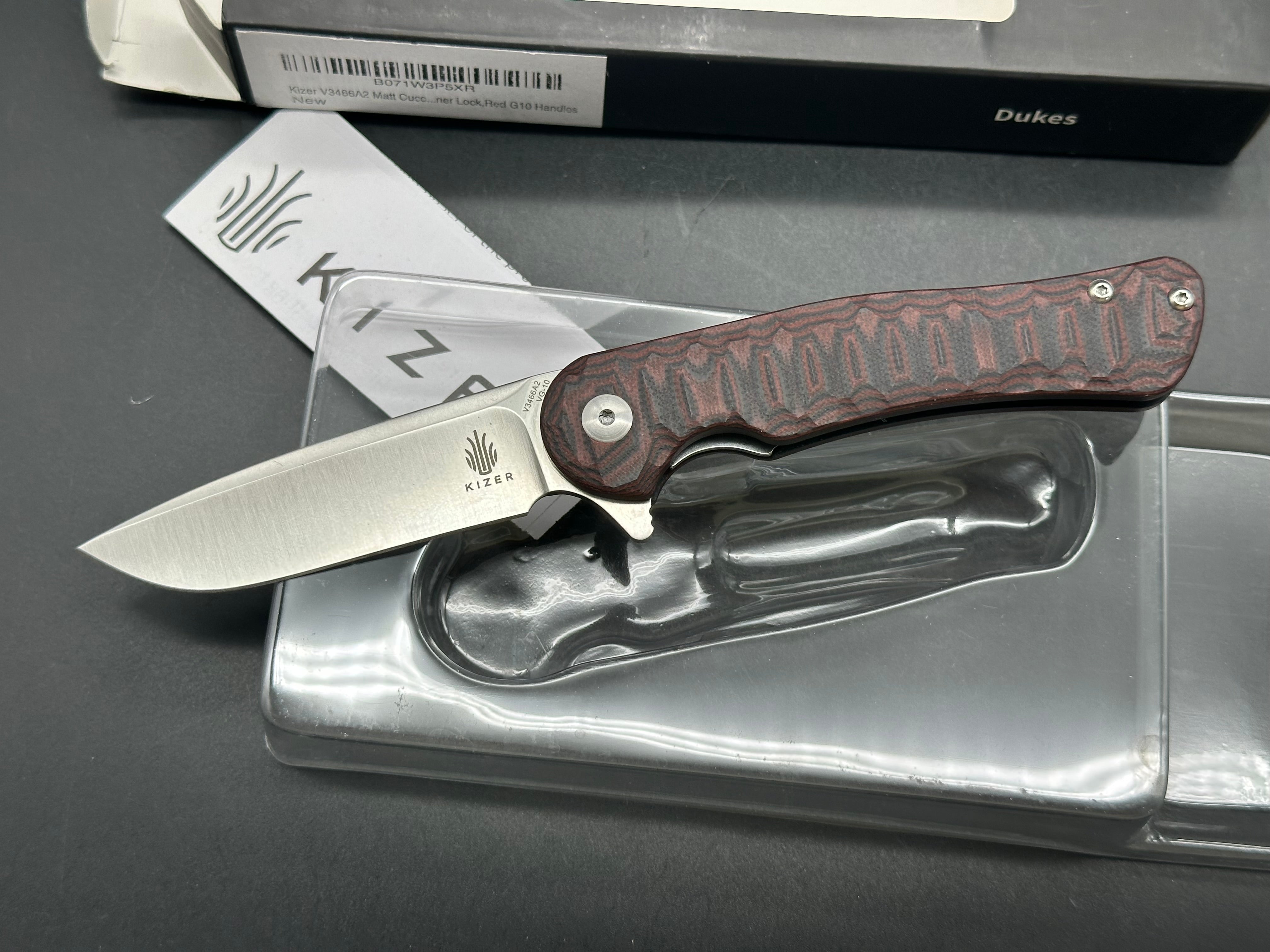 Kizer Dukes A2: Matt Cucchiara design. 3 inch drop point, hollow grind VG-10 blade. Red G-10 handle