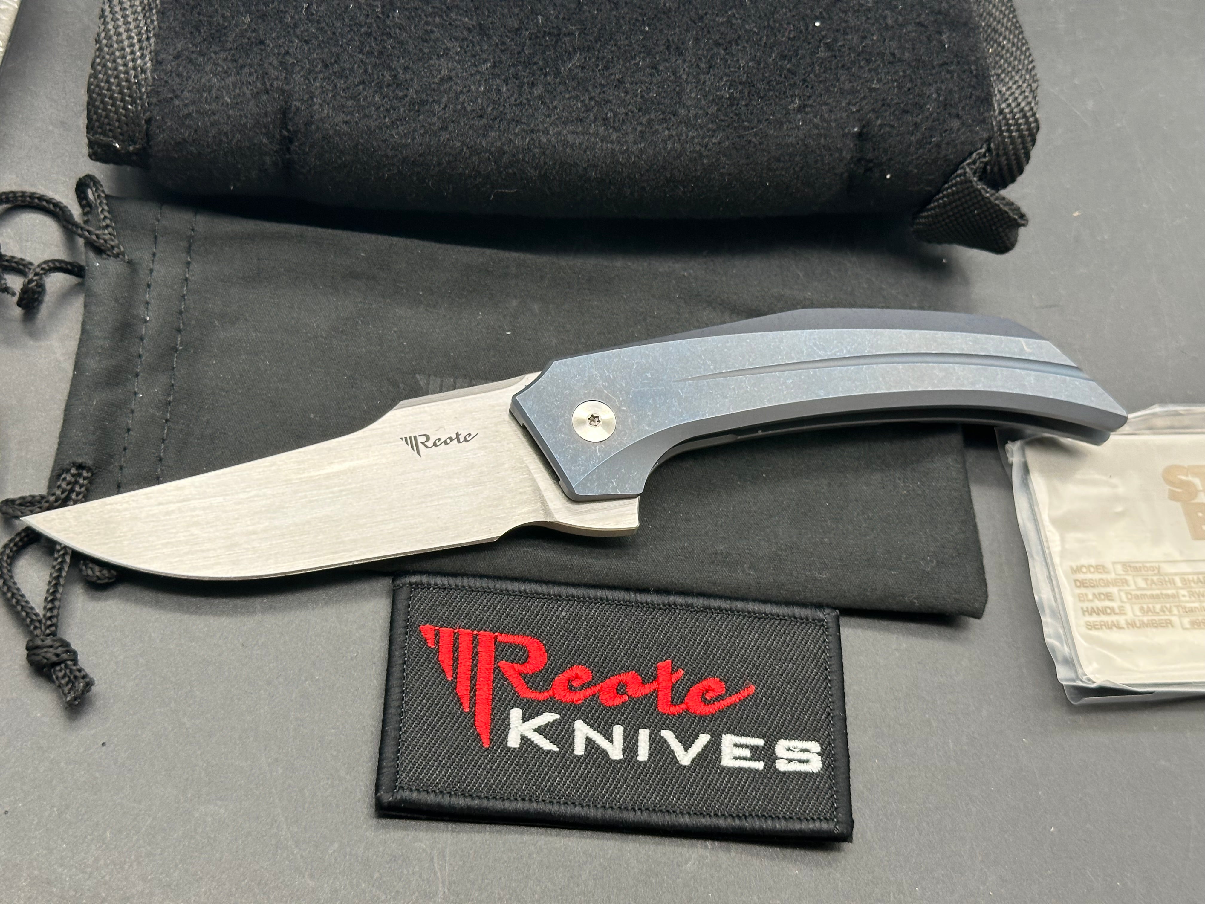 Reate Starboy: Tashi Bharucha design. 3 inch, hand rub, satin, clip point RWL-34 blade. Milled and blue anodized frame