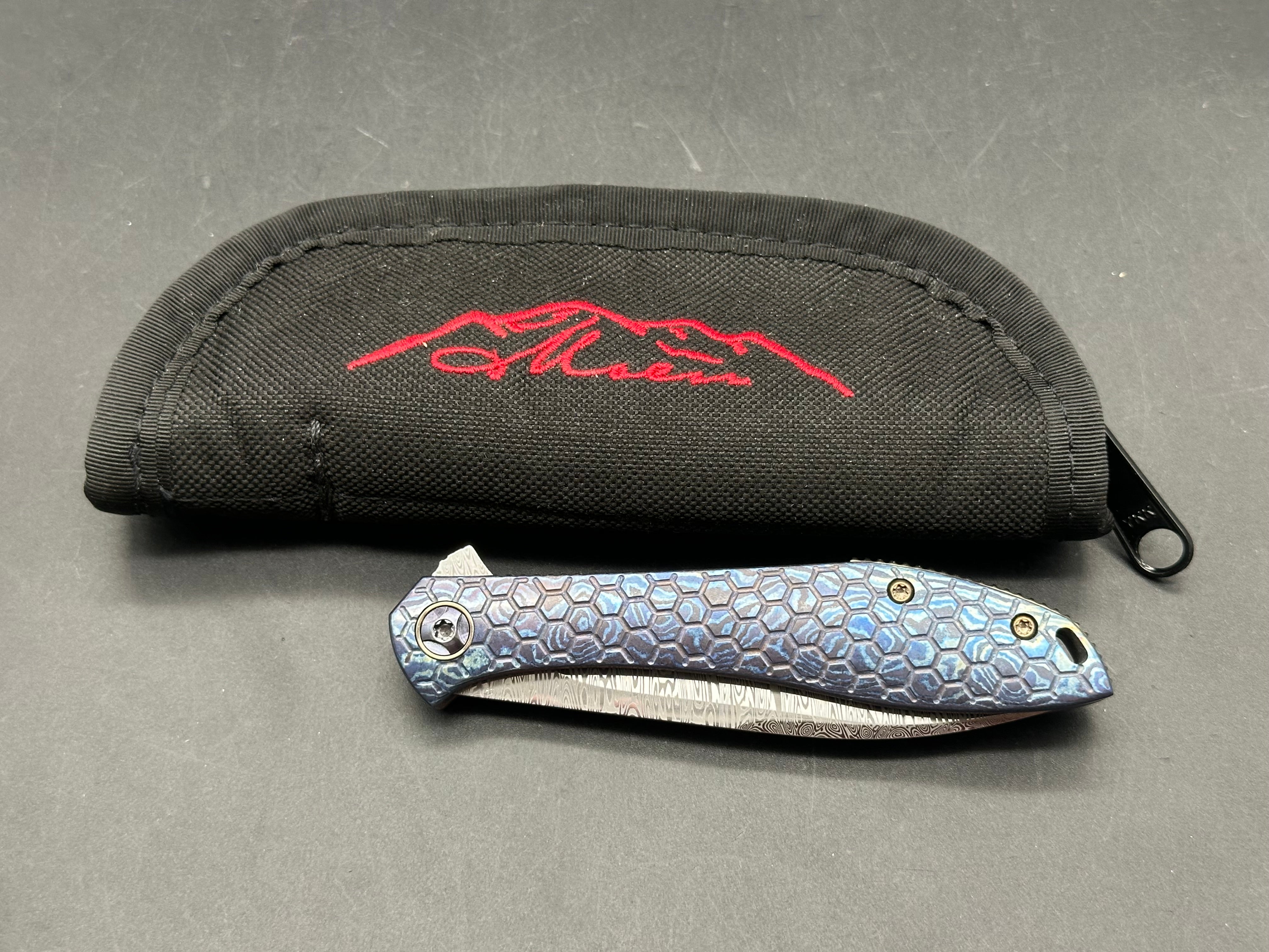 Jerry Moen Mongoose: 3.5 inch Damasteel recurve blade. Milled Mokuti frame with anodized titanium backspacer and clip