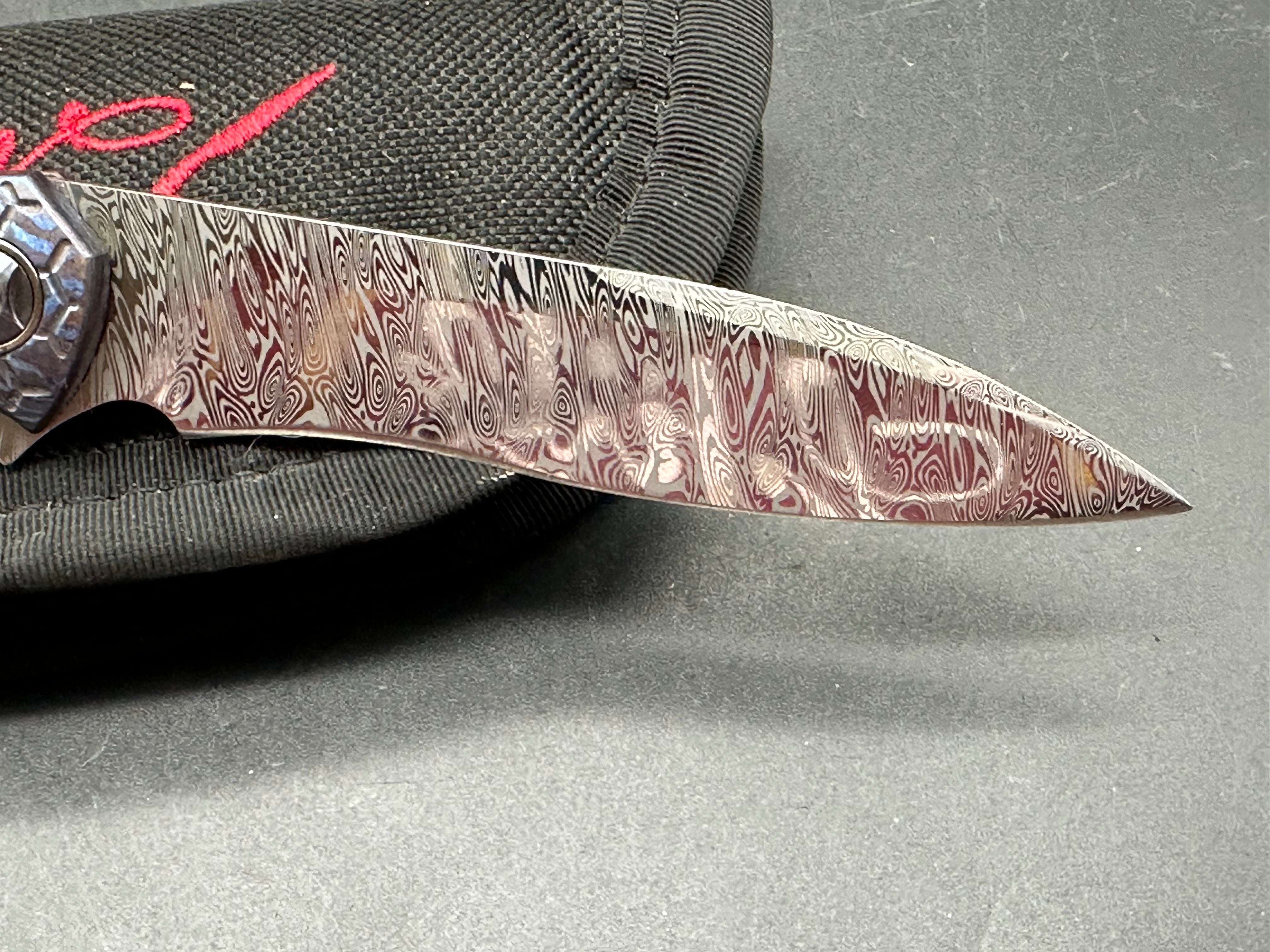Jerry Moen Mongoose: 3.5 inch Damasteel recurve blade. Milled Mokuti frame with anodized titanium backspacer and clip