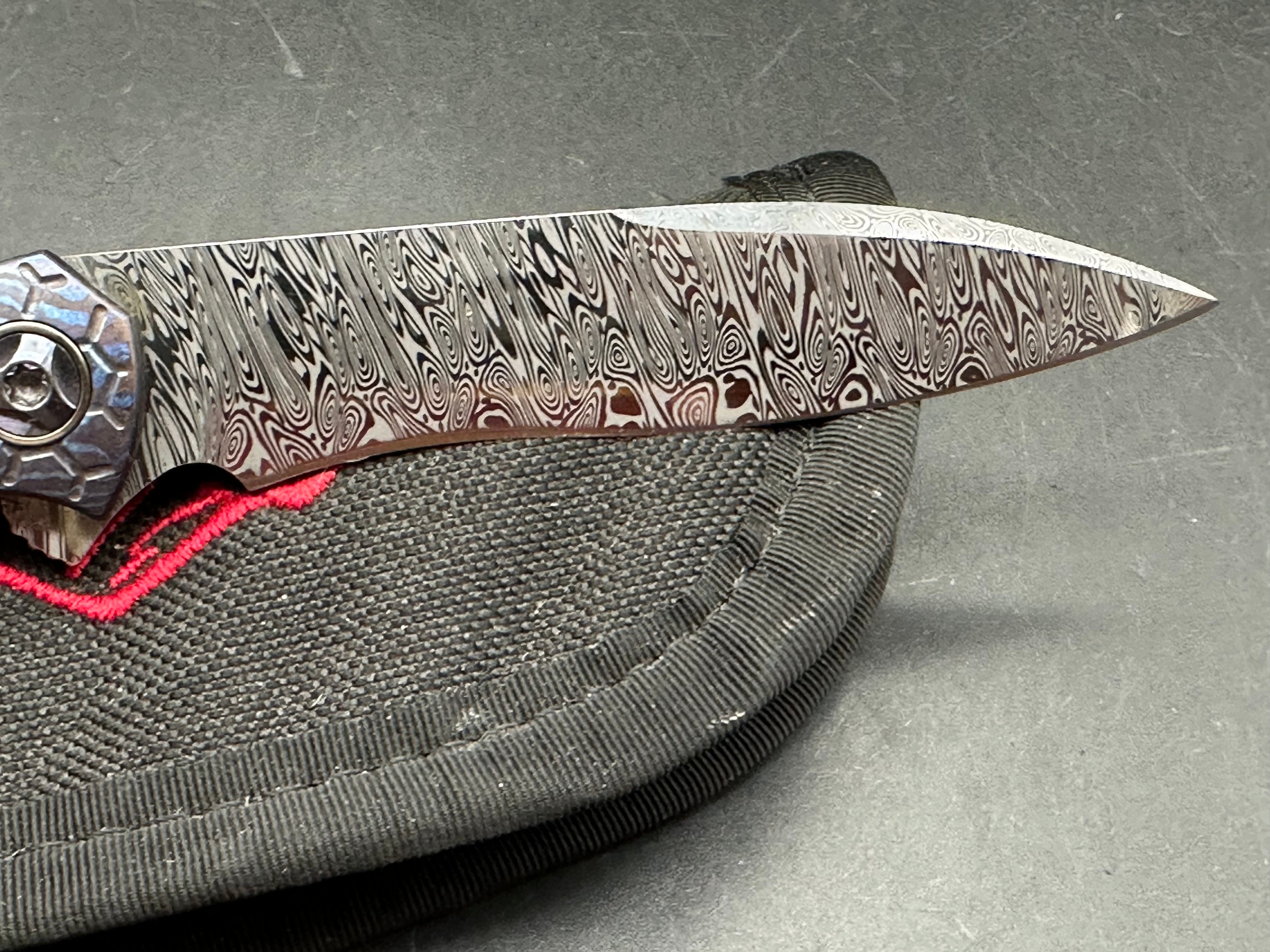 Jerry Moen Mongoose: 3.5 inch Damasteel recurve blade. Milled Mokuti frame with anodized titanium backspacer and clip