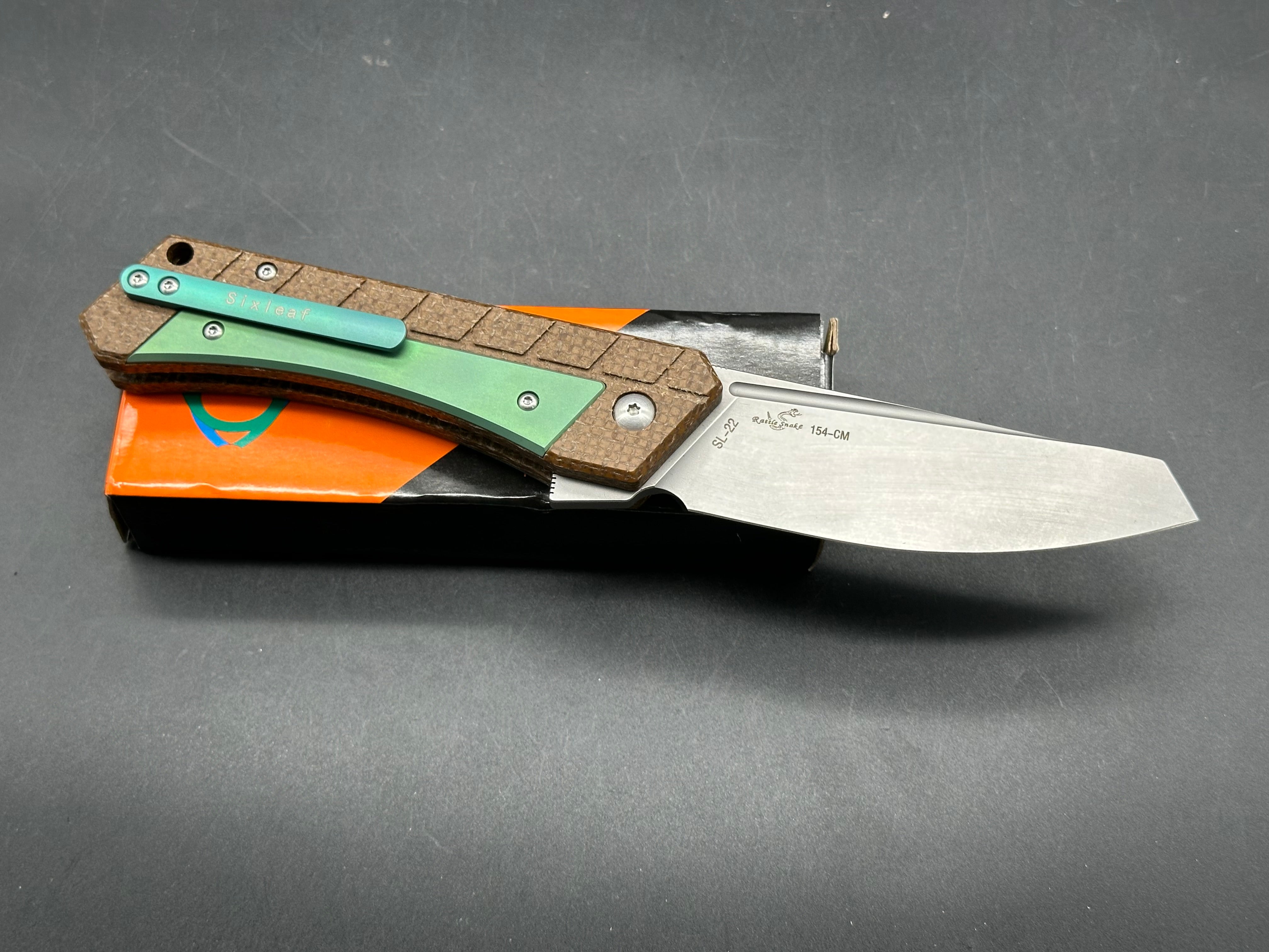 Sixleaf SL-22 GR  Rattlesnake design, button lock, micarta scales with green titanium inserts and pocket clip, 154-CM blade