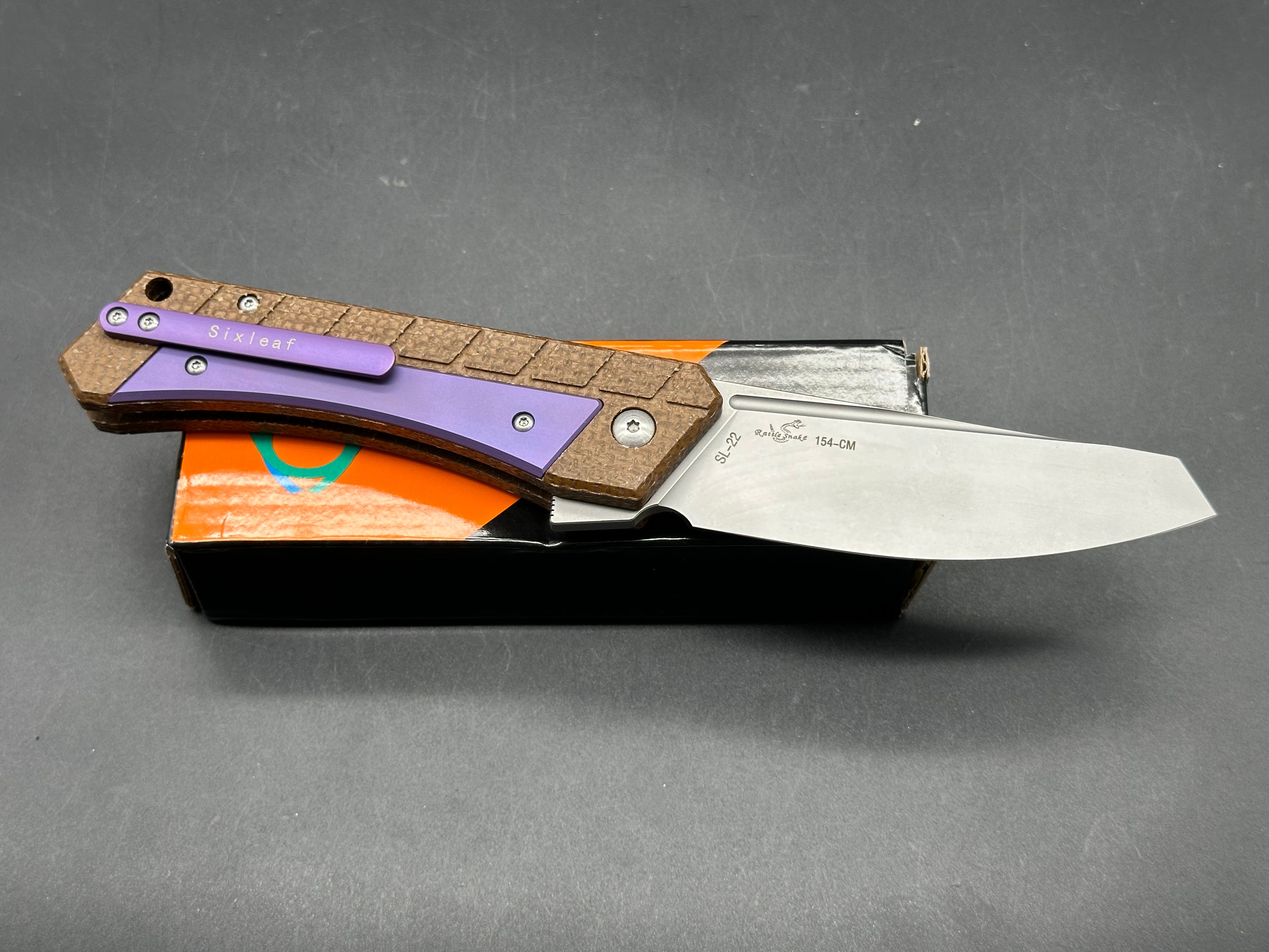 Sixleaf SL-22 PR  Rattlesnake design, button lock, micarta scales with purple titanium inserts and pocket clip, 154-CM blade