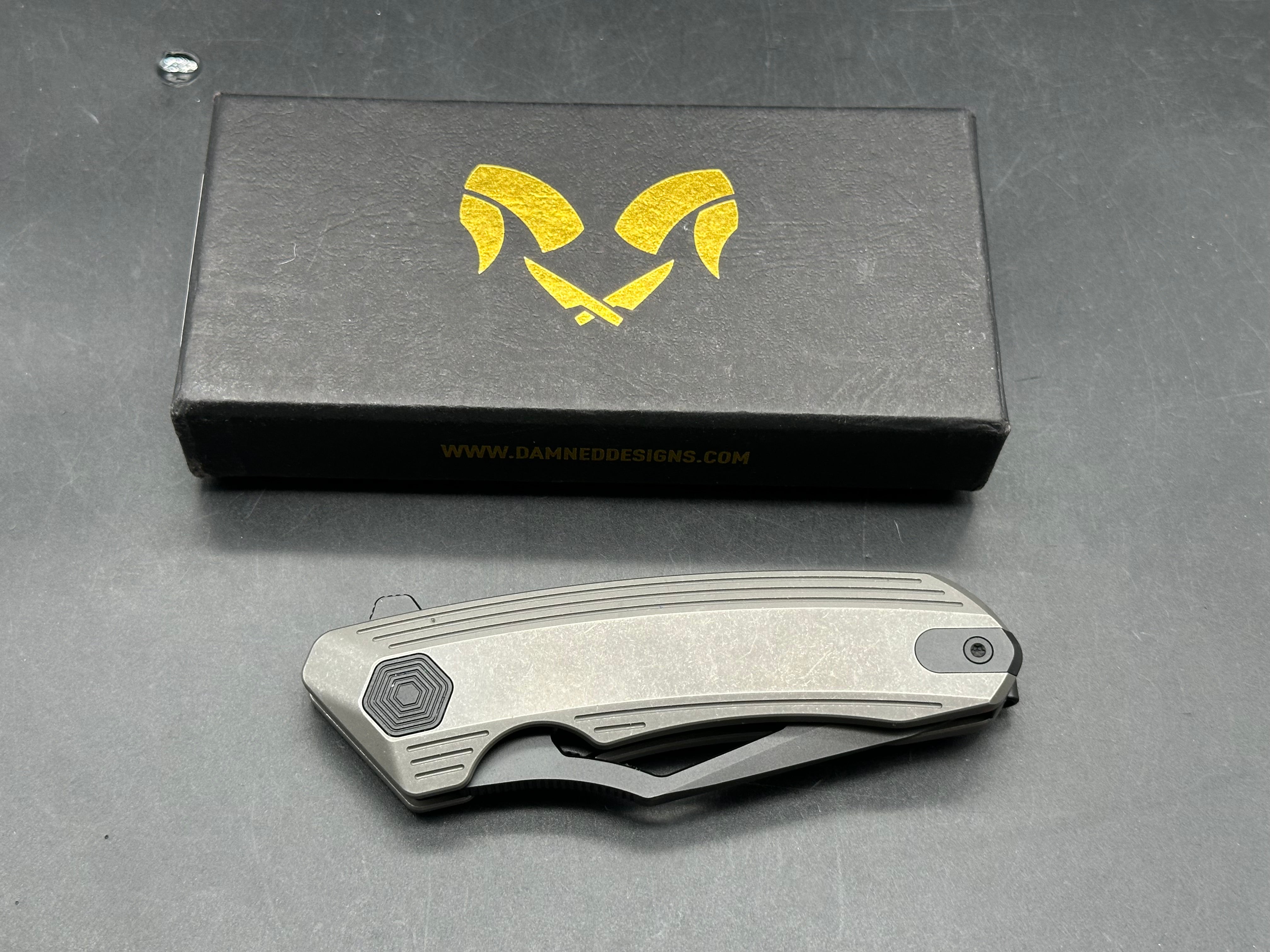 Damned Designs Banshee: 3.1 inch hollow grind, stonewashed, blackwashed CPM-S35VN blade. Ceramic ball bearings