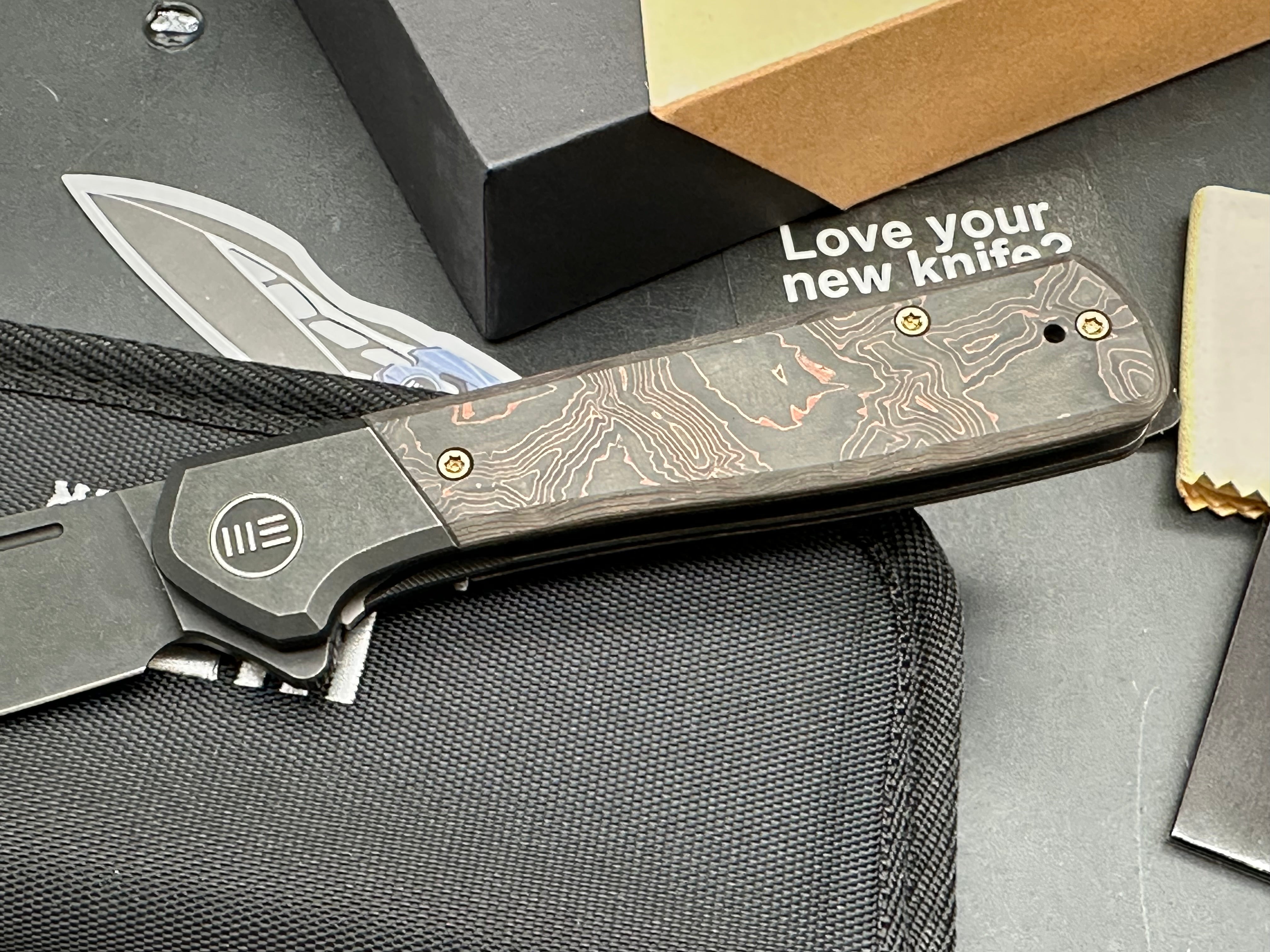WE SOOTHSAYER FOLDING KNIFE BLACK TITANIUM/COPPER FOIL CARBON FIBER INLAY HANDLE 20CV DROP POINT PLAIN EDGE