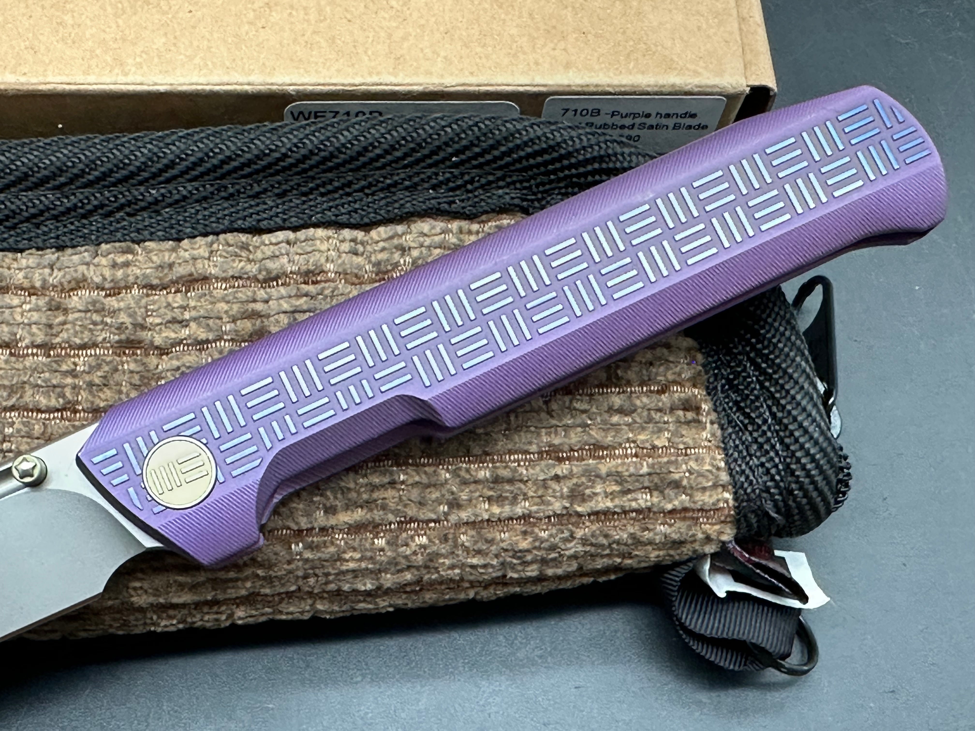 We 710B: 3.85 inch, flat grind, satin, M390 blade. Purple anodized handle. Frame lock. Ceramic bearings