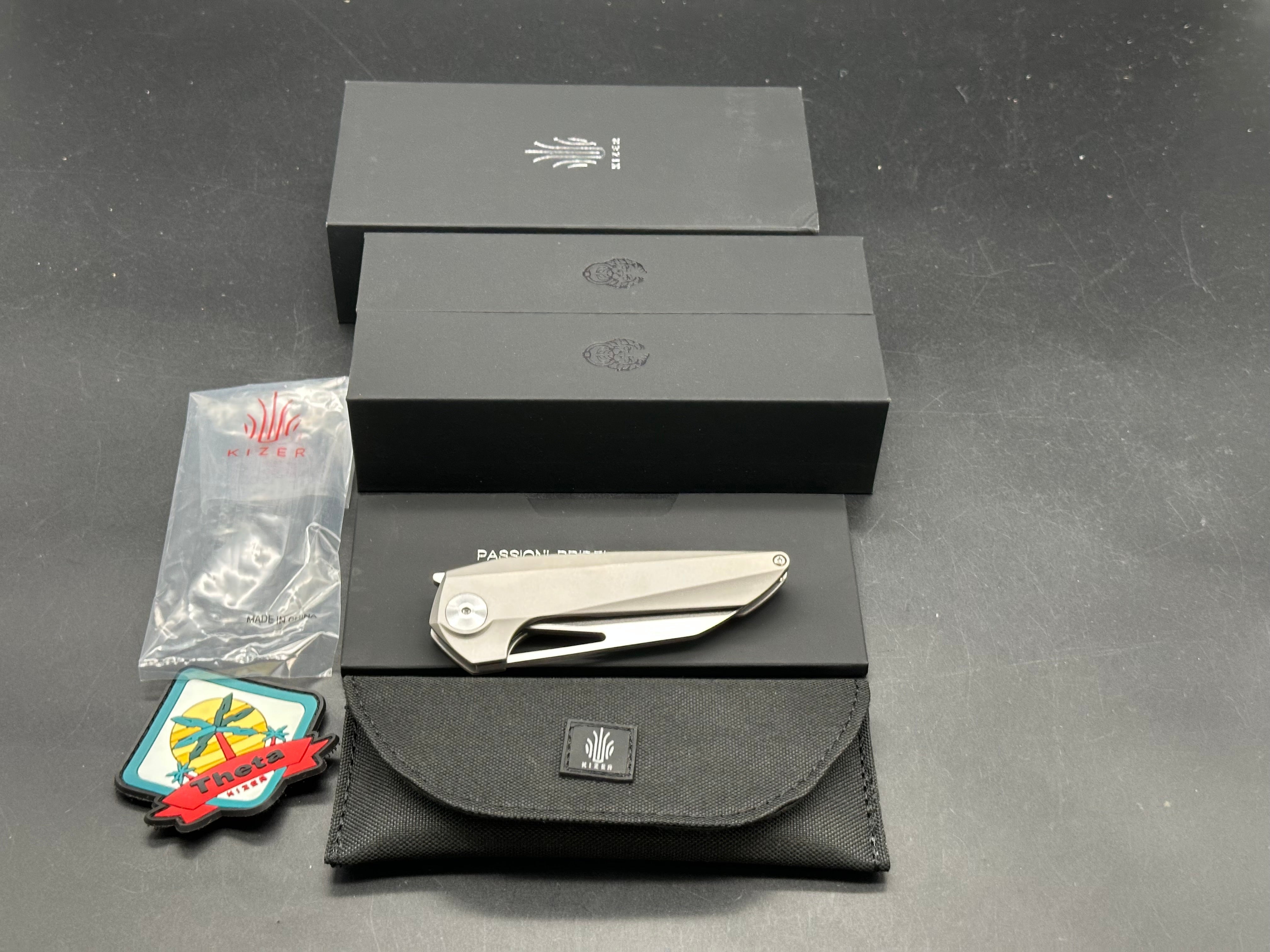Kizer Theta: Elijah Isham design. 3.125 inch, stonewashed, flat grind, Wharncliffe CMP-S35V blade. Titanium handle