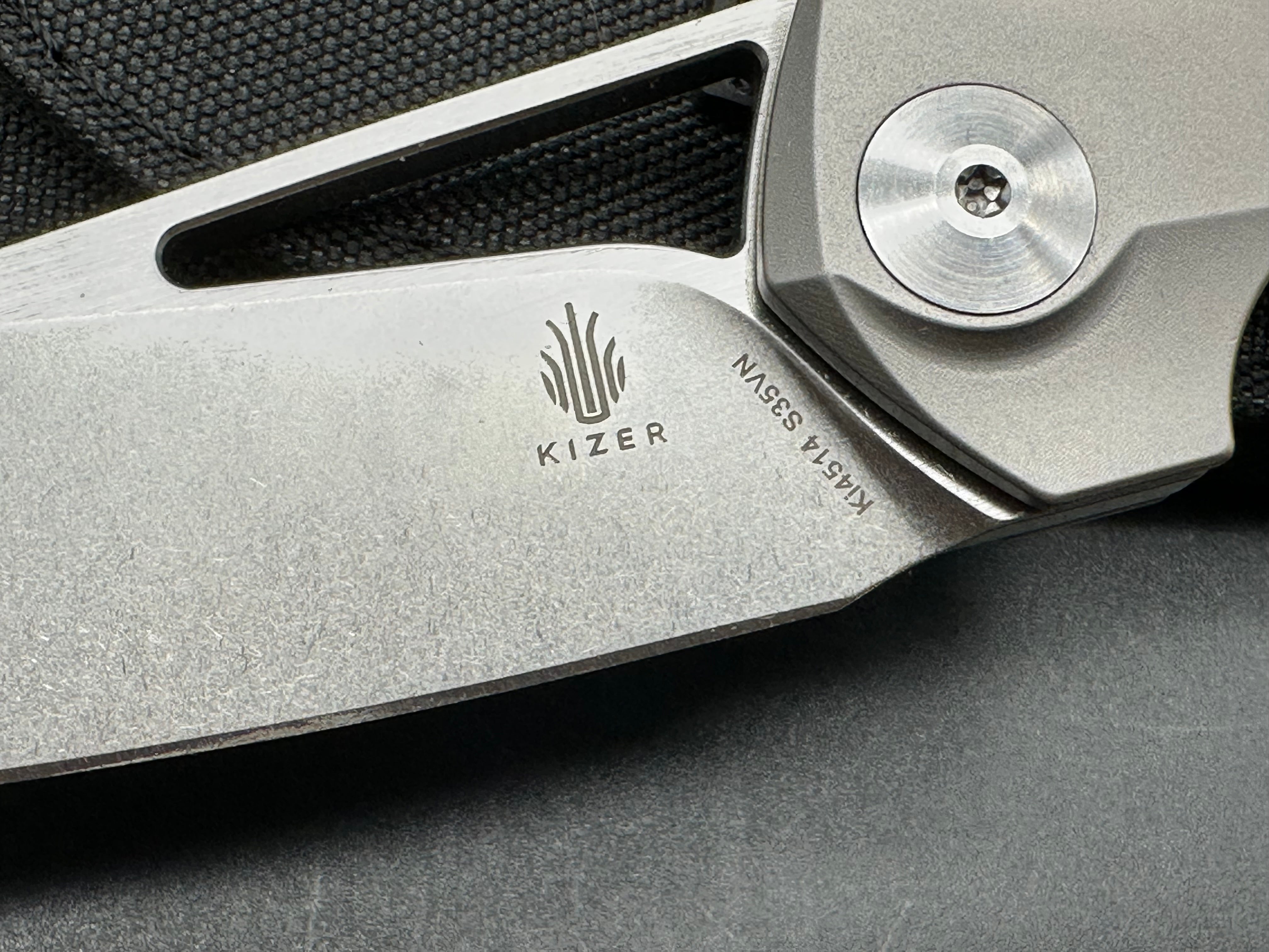 Kizer Theta: Elijah Isham design. 3.125 inch, stonewashed, flat grind, Wharncliffe CMP-S35V blade. Titanium handle