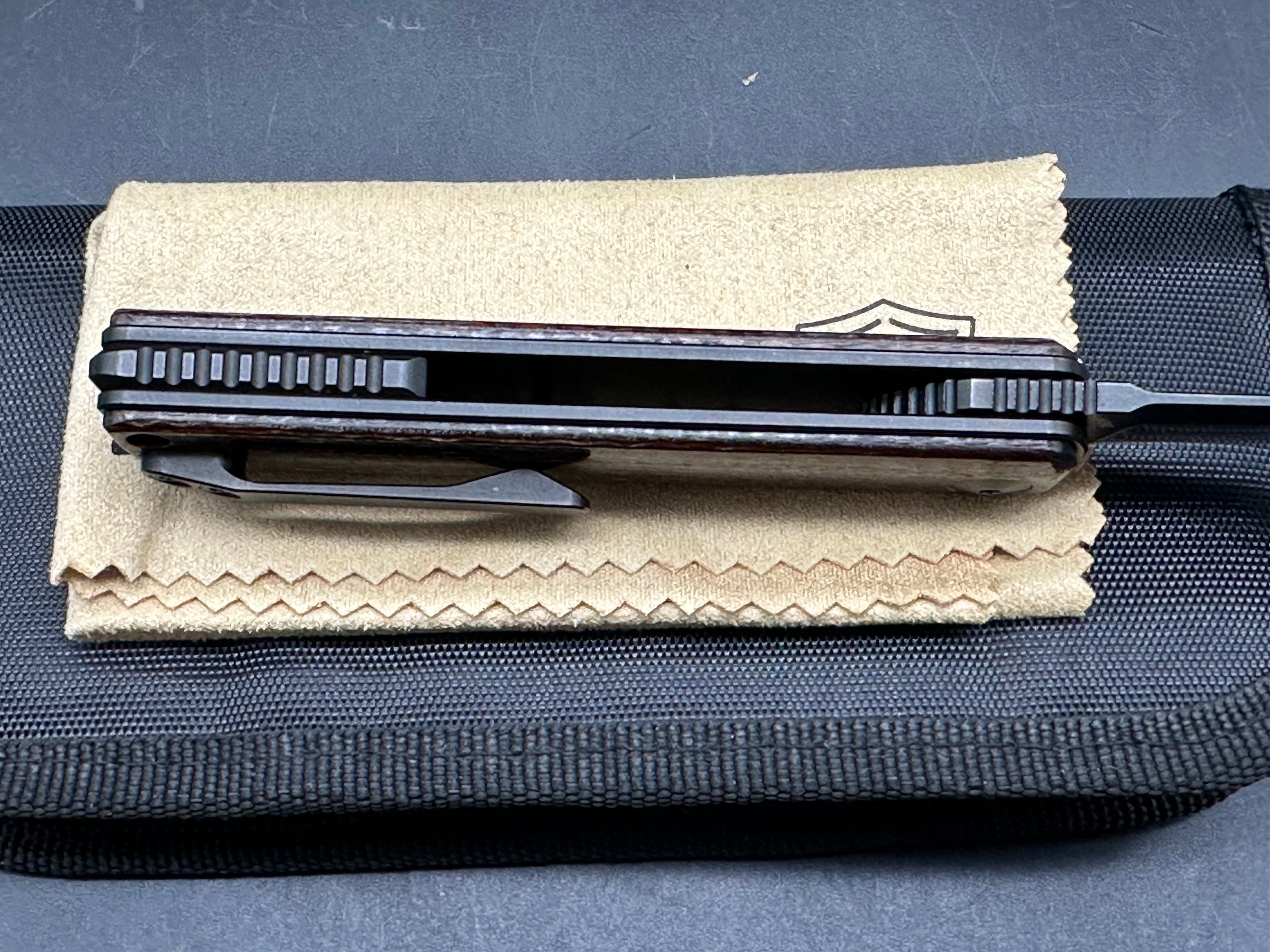 Reate Bushido: 3 inch trailing point, flat grind, blackwash, M390 blade. Front flipper. Blackwash titanium clip. Brown micarta handle