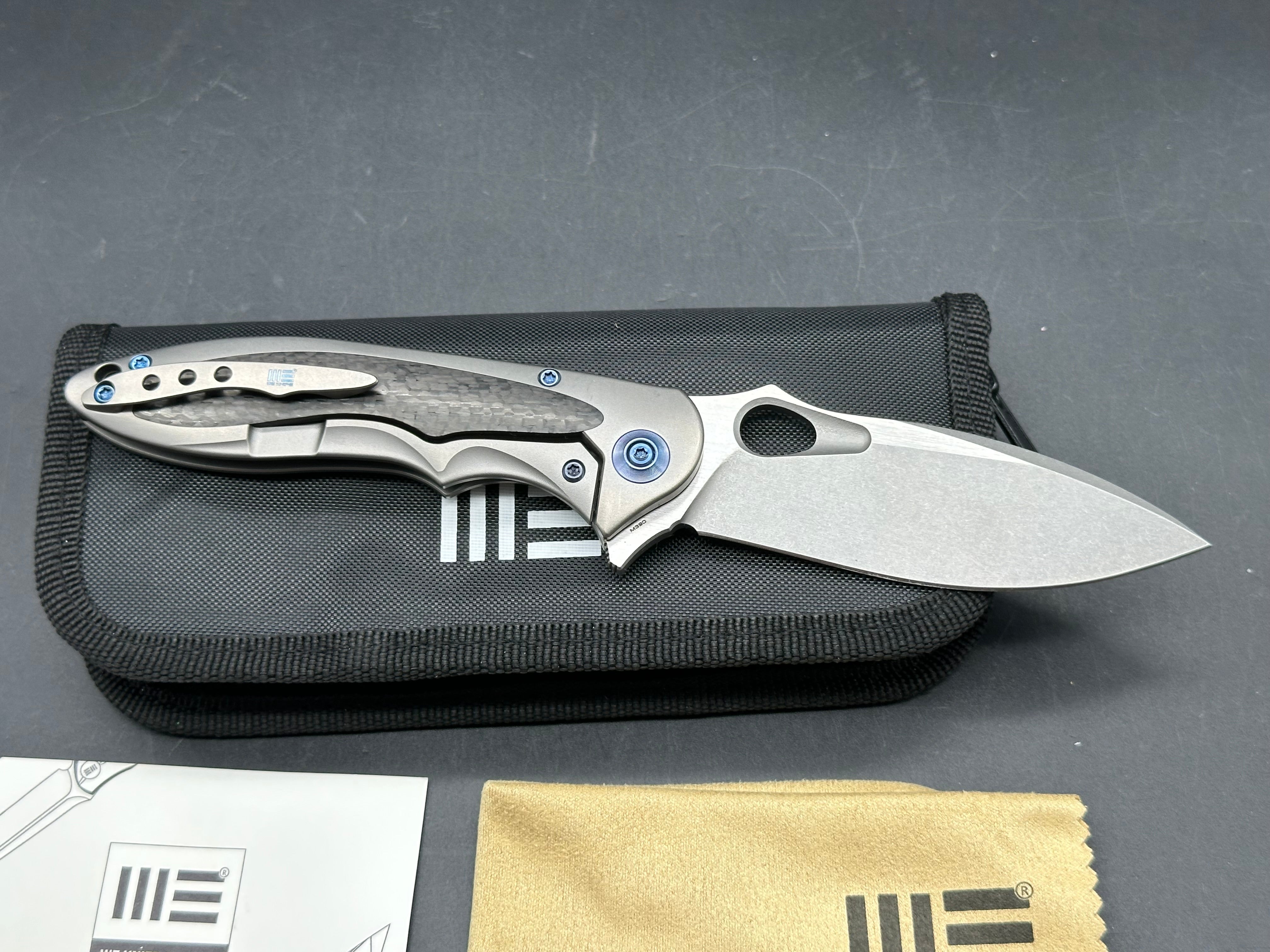 We Knives Zephyr: 3.5 inch drop point, flat grind, Bohler M390 blade. Titanium handle with carbon fiber inset