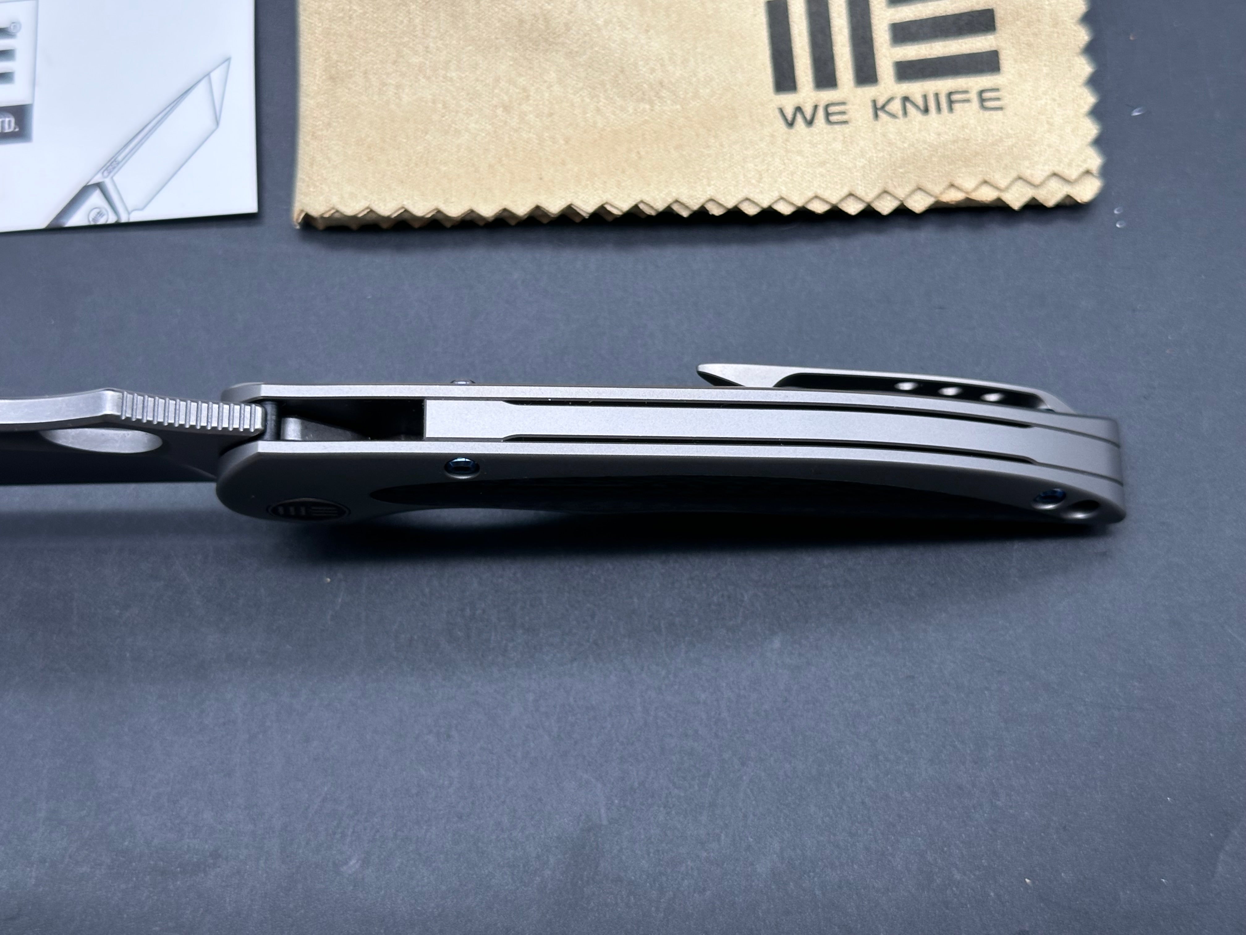 We Knives Zephyr: 3.5 inch drop point, flat grind, Bohler M390 blade. Titanium handle with carbon fiber inset