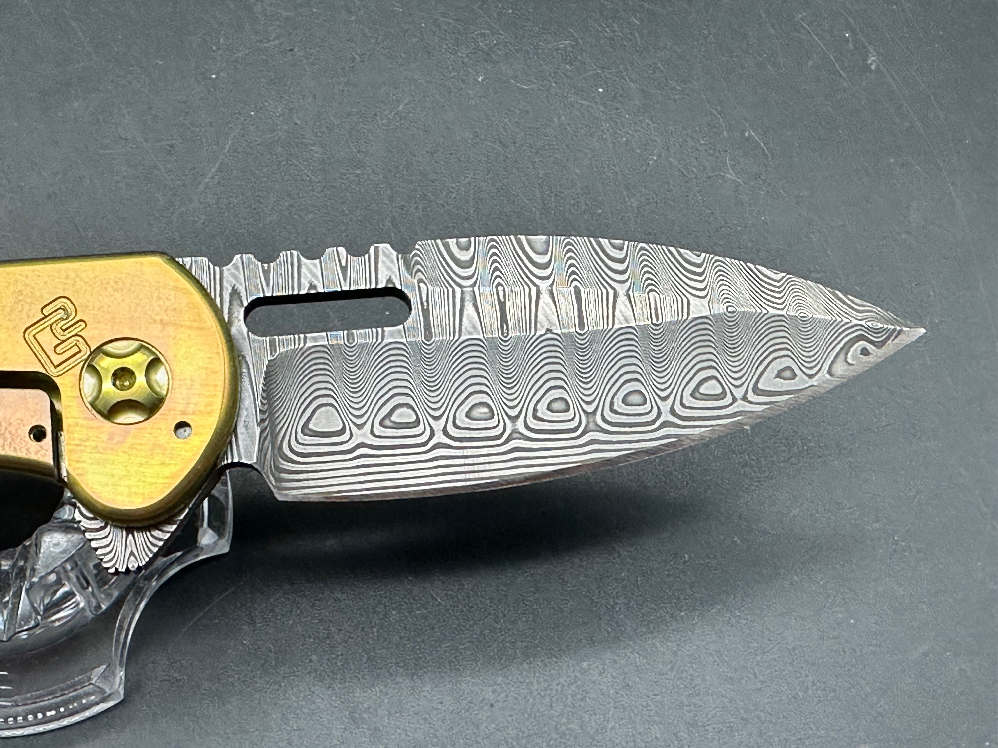 Quest Knives Gent's Spearpoint: 3.125 inch Odin's Eye Damascus blade. Anodized milled titanium frame with carbon fiber inserts