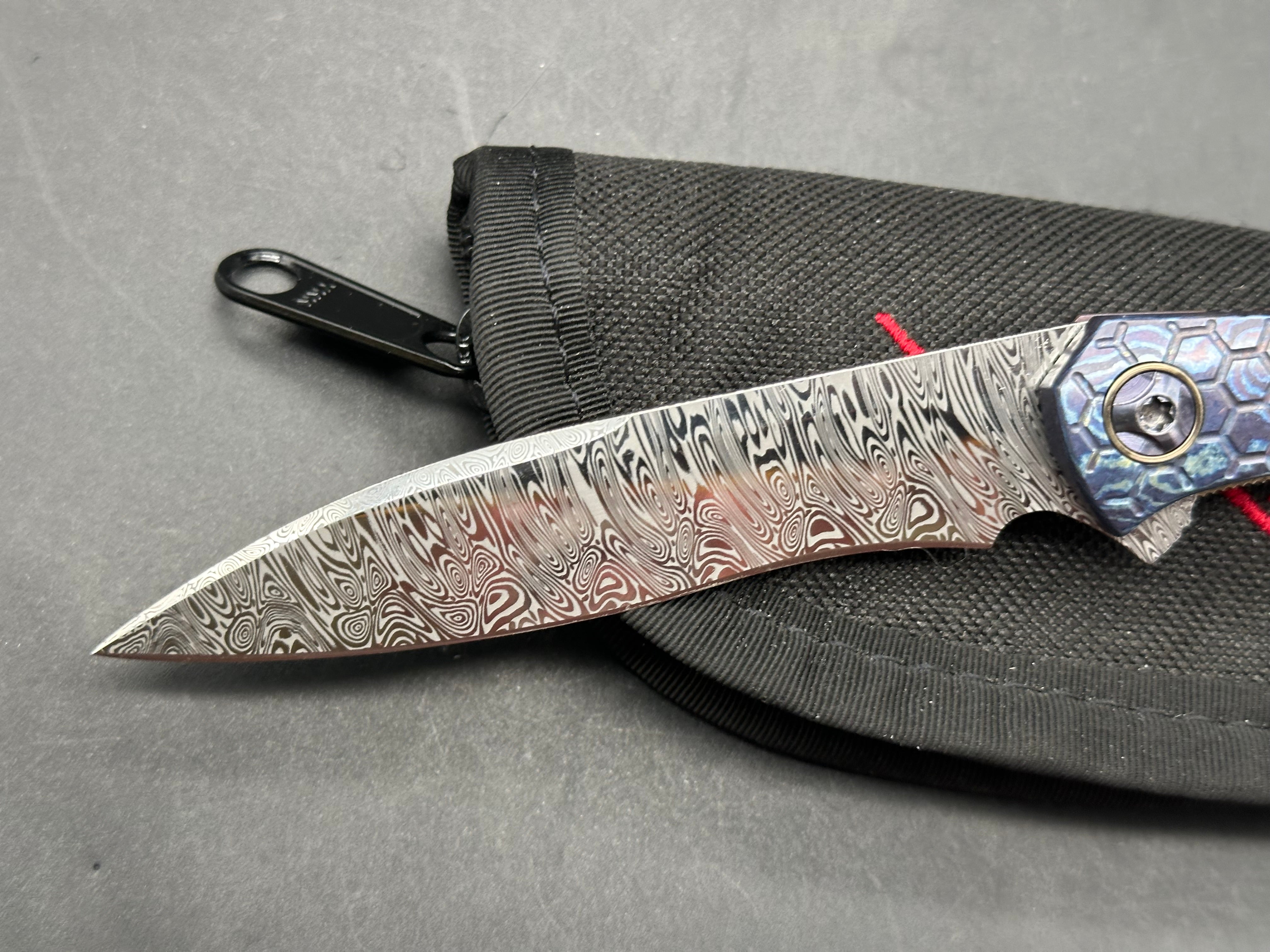 Jerry Moen Mongoose: 3.5 inch Damasteel recurve blade. Milled Mokuti frame with anodized titanium backspacer and clip