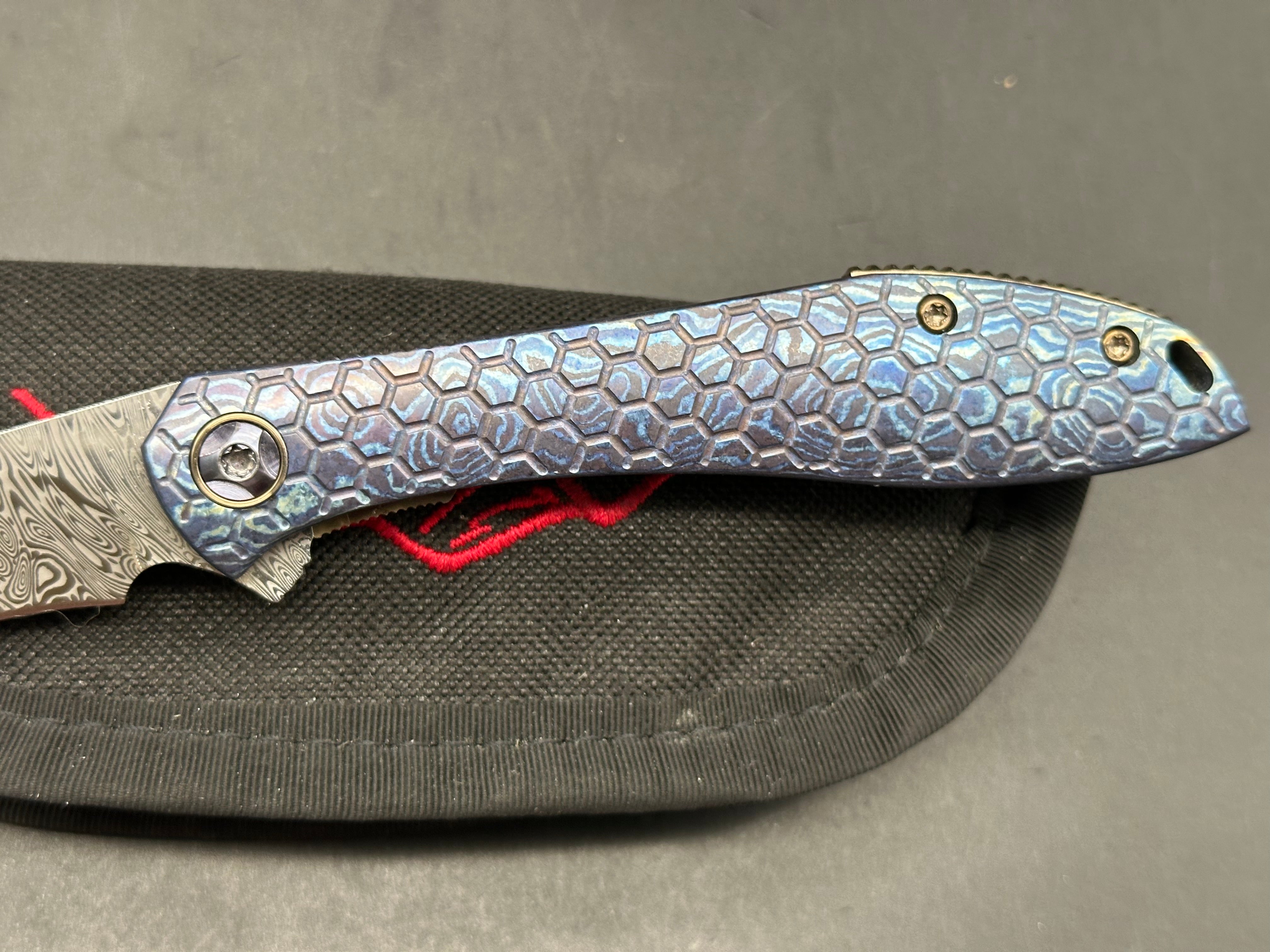 Jerry Moen Mongoose: 3.5 inch Damasteel recurve blade. Milled Mokuti frame with anodized titanium backspacer and clip
