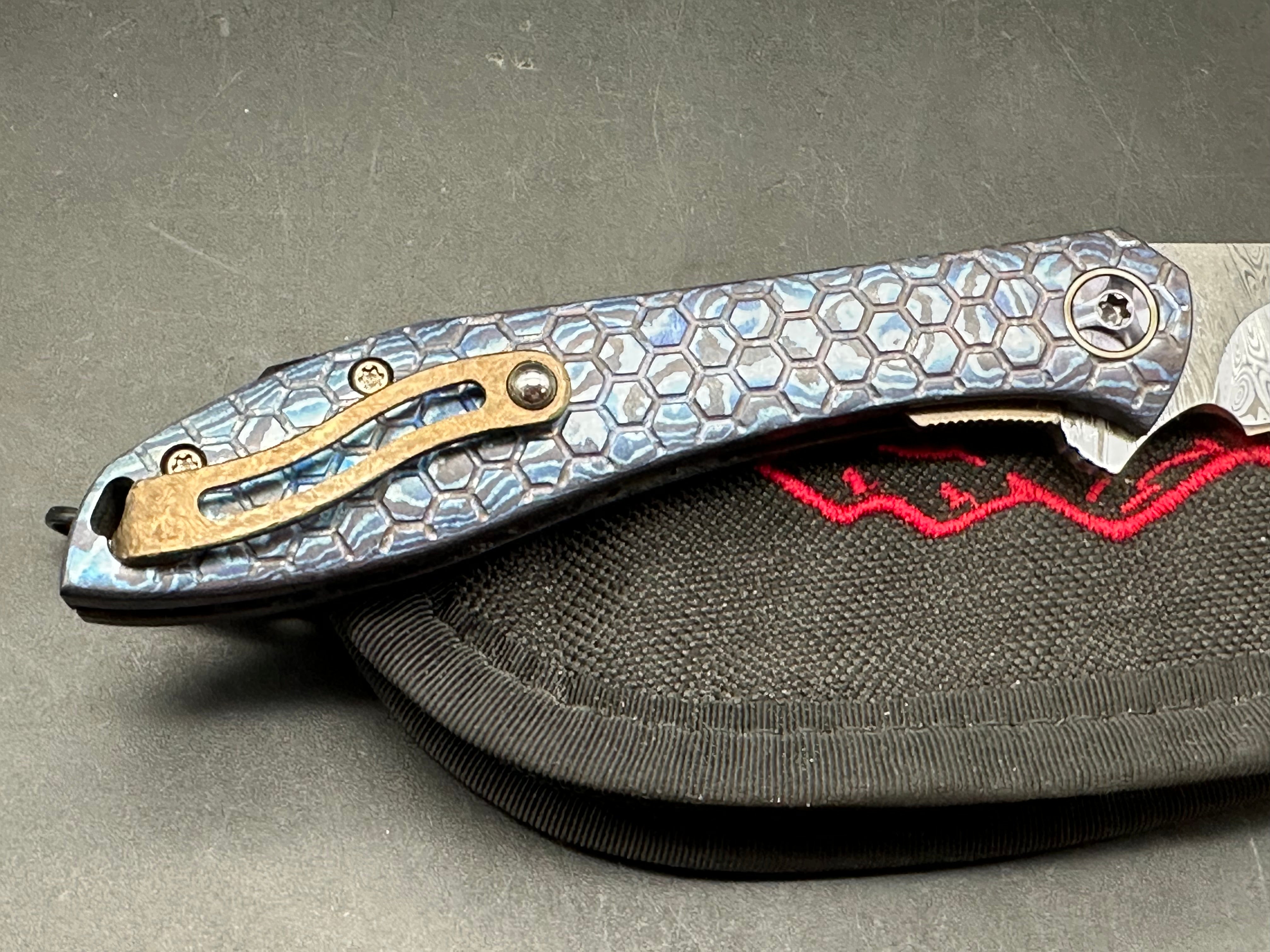 Jerry Moen Mongoose: 3.5 inch Damasteel recurve blade. Milled Mokuti frame with anodized titanium backspacer and clip